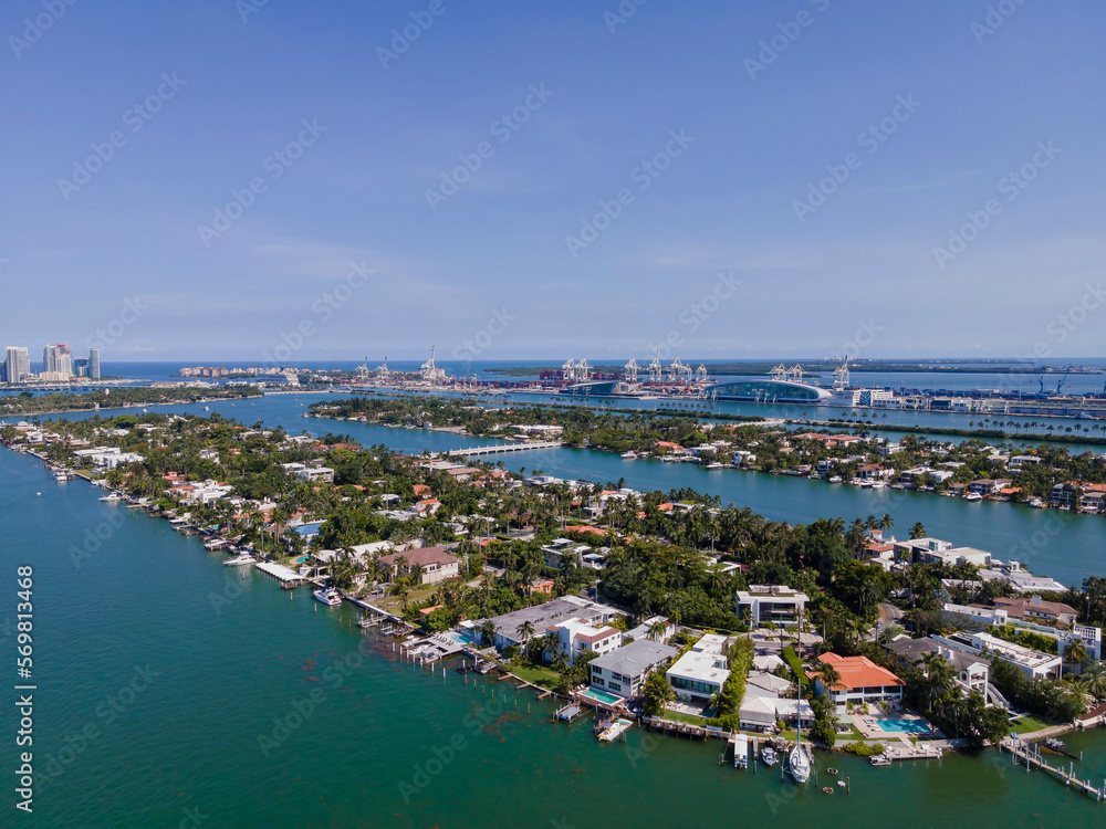 Aerial view of properties amidst the Intracoastal Waterway in Miami Florida. Waterfront homes and buildings has a scenic view of the man-made inland water channel with boats against blue sky.