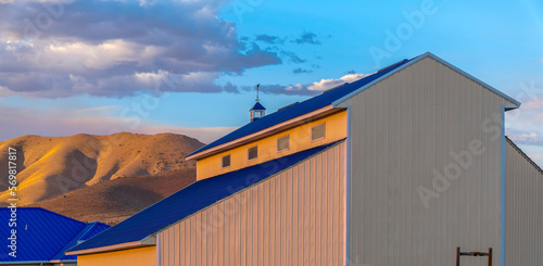 Eagle Mountain, Utah- Barn building against the mountain during sunset. Barn with beige steel wall claddings and blue roofs against the mountain and sky. photo