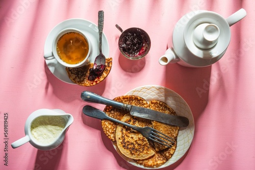 Still life - blueberry jam, green tea and pancakes. Food and drink on a pink background