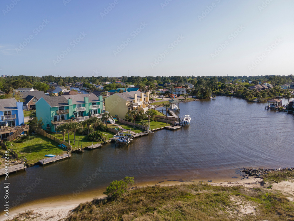 Intracoastal waterway at the front of residential buildings at Navarre, Florida. Colorful apartments and family homes with tropical trees and private docks at the front against the clear skyline.