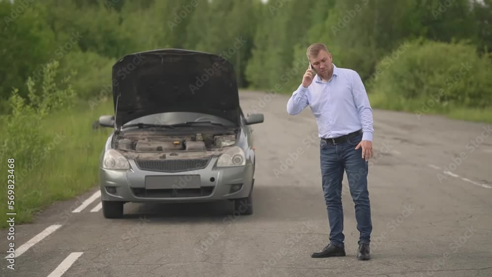 the man crashed the car and smoke from under the hood. a man swears with someone on the phone. slow motion video. High-quality FullHD video recording the man crashed the car and smoke from under the hood. a man swears with someone on the phone. slow motion video. High-quality FullHD video recording