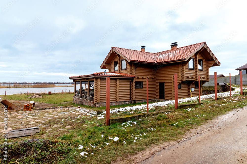 A wooden, log house on the shores of a large lake. Construction in progress
