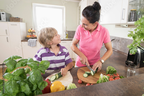 Woman with her son chopping vegetables in kitchen, Bavaria, Germany photo