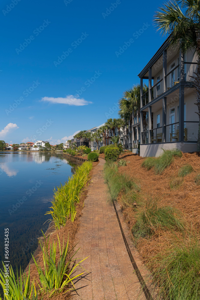 Bricks walkway near Four Prong Lake in a neighborhood at Destin, Florida in a vertical shot view. Narrow bricks pavement path along the lake and neighborhood with trees and plants outside.