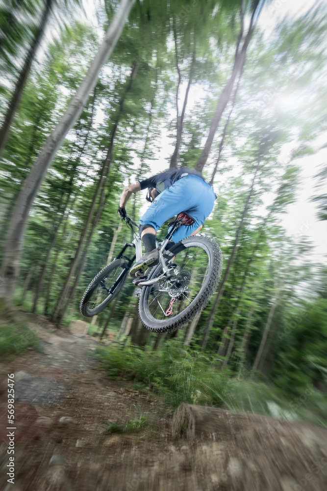 Mountain biker performing jump on bicycle on single track in forest, Bavaria, Germany Mountain biker performing jump on bicycle on single track in forest, Bavaria, Germany