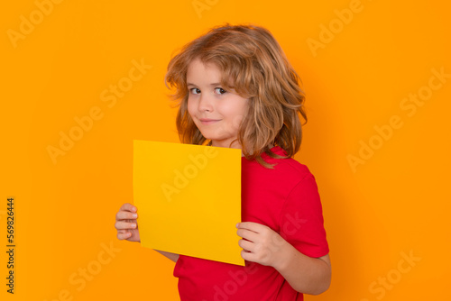 Kid showing blank banner on yellow isolated background . Advertising billboard, placard. Child hold empty color blank sheet of paper, copy spase. Poster for your text information.