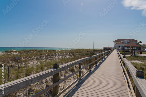Wooden walkway and beach houses against blue sky in Destin Florida. Relaxing coastal scenery with ocean  blue sky  and waterfront residences on a sunny day.
