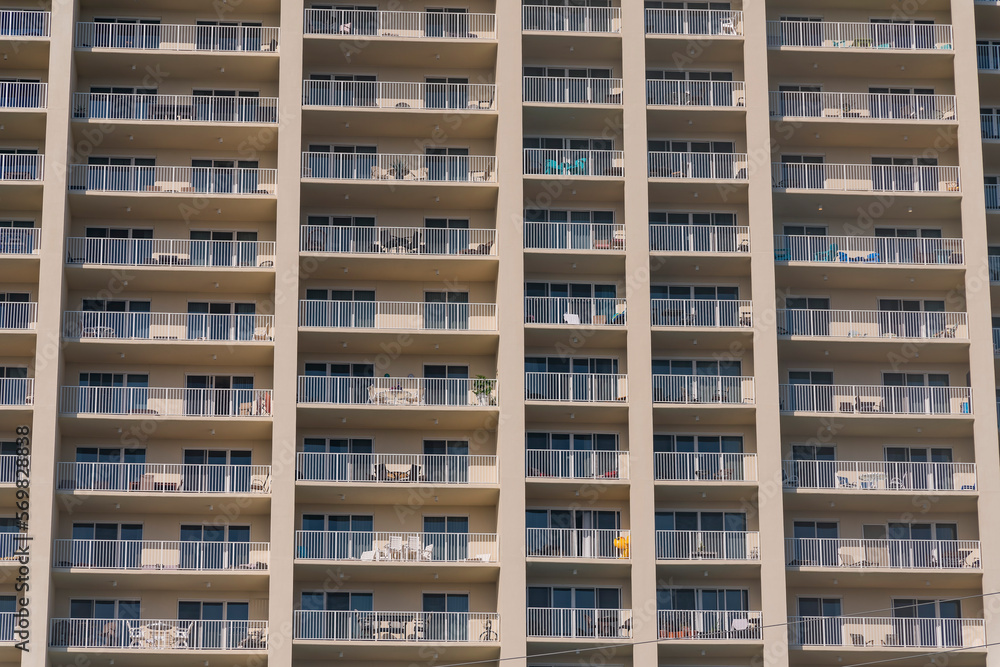 Hotel Apartment building facade with continuous balconies patter in Destin, Florida. Modern multi-storey building exterior with white railings and sliding doors on its balconies.