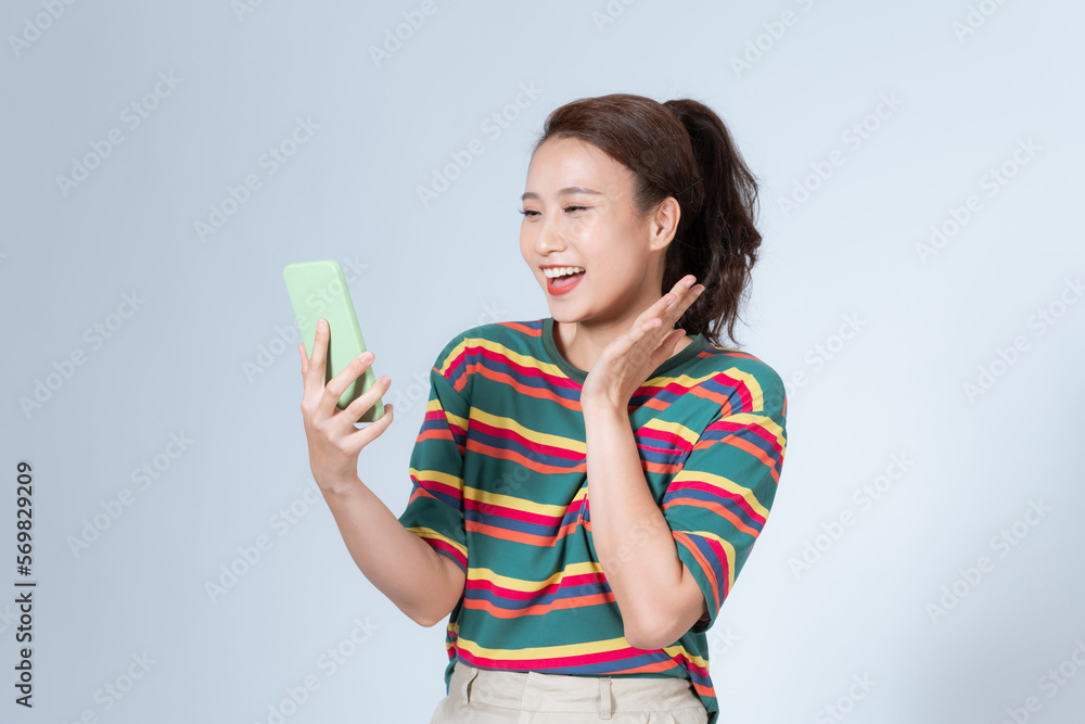 Portrait of pretty woman amazed holding mobile phone staring palm near face surprised isolated on gray background Portrait of pretty woman amazed holding mobile phone staring palm near face surprised isolated on gray background