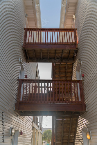 Stairwell in between two buildings with two landings and railings- Destin  Florida. Views of two landings of a wooden stairwell outside connecting the buildings with white wood sidings.