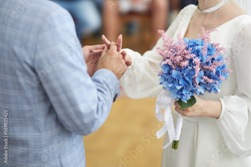 the newlyweds exchange rings, the bride holds a bouquet of blue hydrangeas and dried flowers in her hands, close-up. wedding concept
