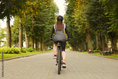Woman riding bicycle on road outdoors, back view