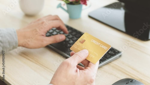 Male hands holding  gold credit card making e bank online payment. Man consumer paying for purchase in web store using laptop technology. Ecommerce website payments concept.