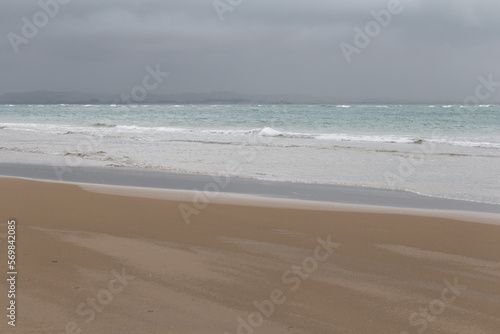 Picturesque landscape with sand beach, turquoise sea and rainy sky on background, Pouto Beach, New Zealand.