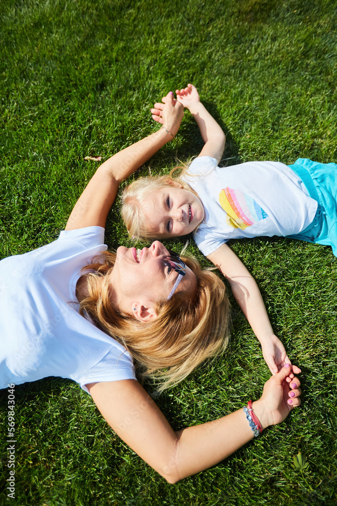 A little girl with her mom is lying on the grass A little girl with her mom is lying on the grass