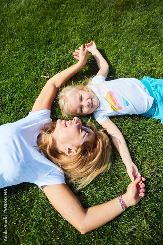 A little girl with her mom is lying on the grass