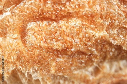 Natural Background from a fragment of a crust of wheat bread, a French baguette. Selective focus. Close-up. Space for lettering and design.