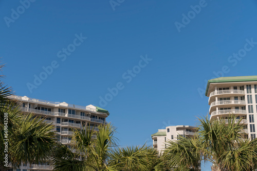 Apartment buildings with palm trees outdoors at Destin, Florida. Views of three multi-storey apartments with balconies against the blue skyline.