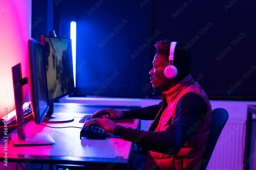 Young African man playing video game on computer. Streamer guy sitting at home and plays another match Young African man playing video game on computer. Streamer guy sitting at home and plays another match