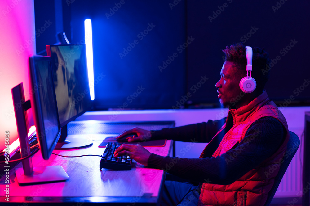 Young African man playing video game on computer. Streamer guy sitting at home and plays another match Young African man playing video game on computer. Streamer guy sitting at home and plays another match