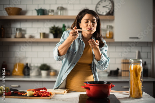 Wallpaper Mural Beautiful pregnant woman preparing delicious food. Smiling woman having fun while cooking at home Torontodigital.ca