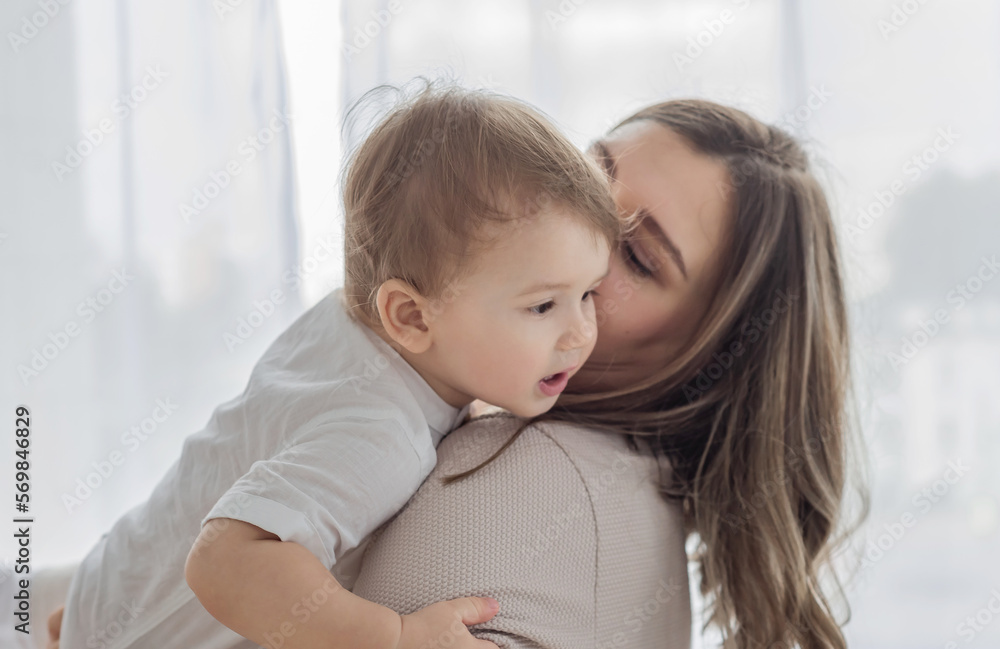 A young mother kisses her little son. Happy family concept A young mother kisses her little son. Happy family concept