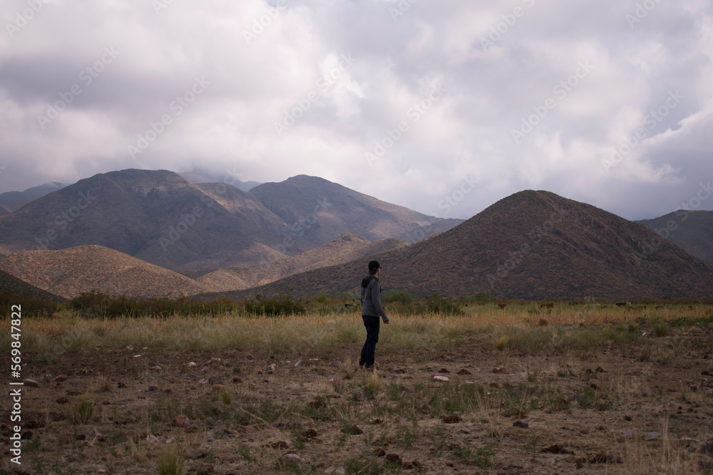 man walking in the field at the foot of the Andes mountain range in Me