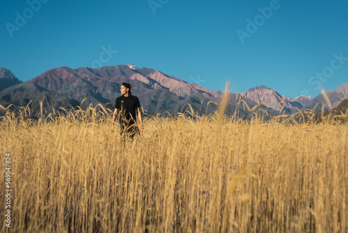 young man walking in the field next to the Andes mountain range photo