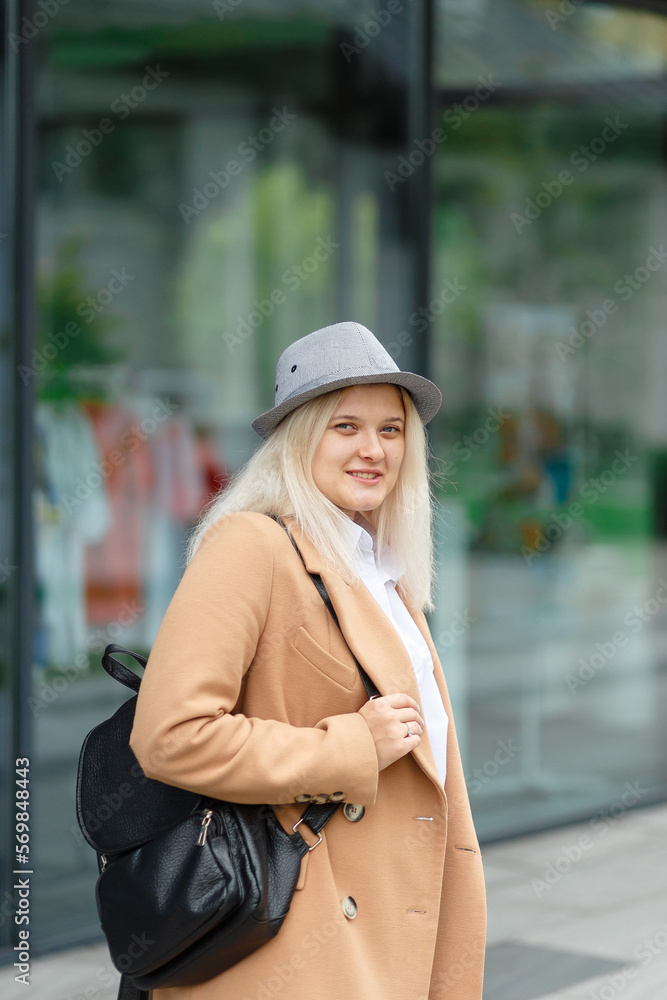 smiling woman blonde in a coat and a backpack in her hands on campus smiling woman blonde in a coat and a backpack in her hands on campus