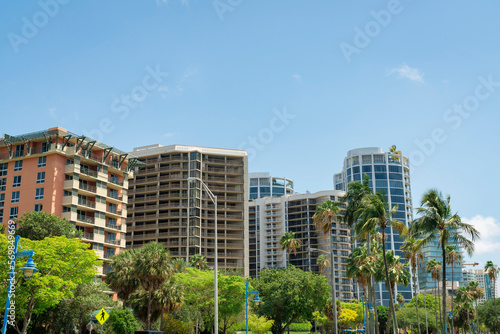 Miami, Florida- Views of modern residential buildings from below. There are views of street lights near the trees below and views of condominium buildings against the clear sky background.