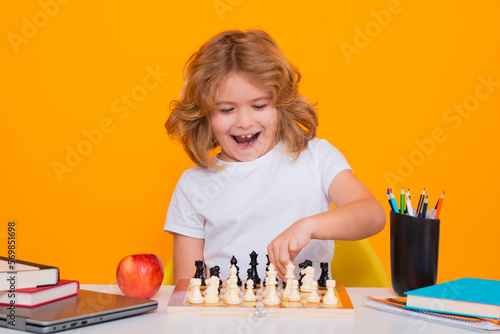 Child with chess on yellow isolated studio background. Kid playing chess. Clever child thinking about chess. Kids early development.