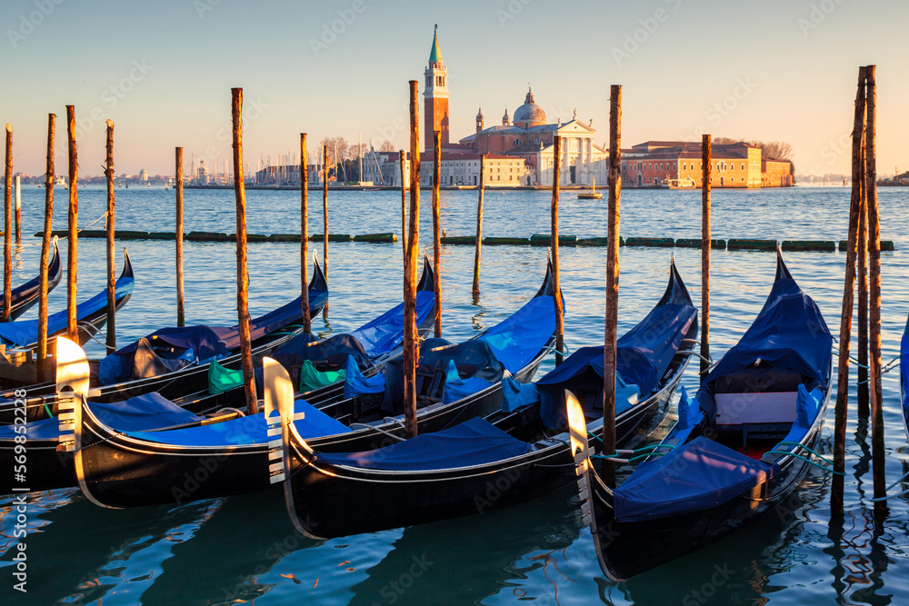 Venezia. Gondole al palo al Molo di Palazzo Ducale verso l'isola di San Giorgio Maggiore al tramonto