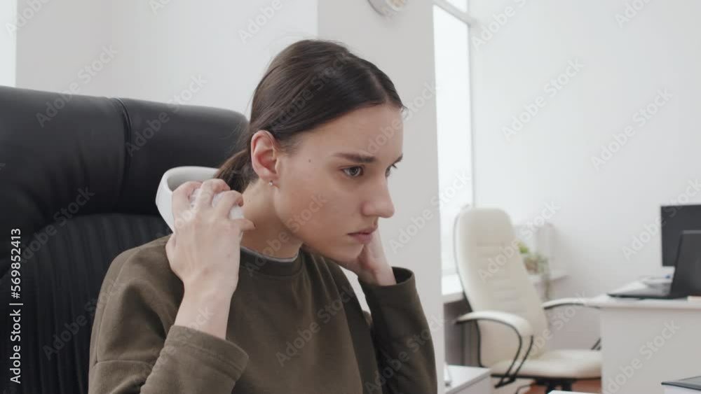 YOung Caucasian woman working in office putting on wireless headphones and turning on her favourite music playlist YOung Caucasian woman working in office putting on wireless headphones and turning on her favourite music playlist