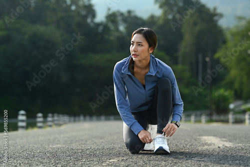 Image of asian woman tying shoelace before running outdoors. Fitness, sport and healthy lifestyle concept
