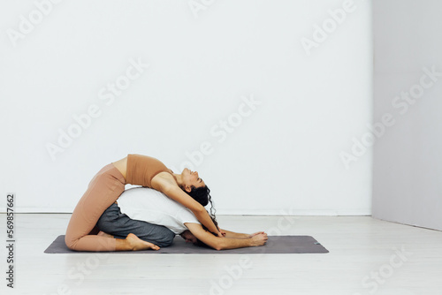acrobatics woman stretches her back on a man training yoga classes in the gym