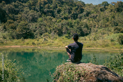 Hombre sentado sobre una roca viendo al lago