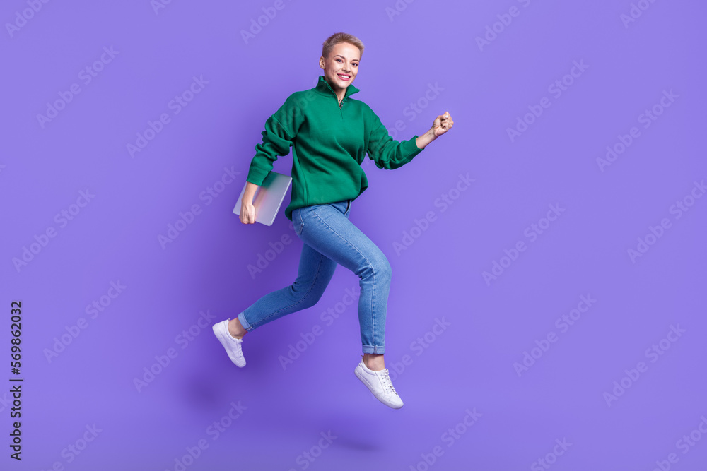 Full length photo of pretty sweet lady wear green sweater running jumping holding gadget isolated violet color background