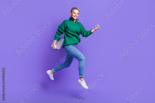 Full length photo of pretty sweet lady wear green sweater running jumping holding gadget isolated violet color background © deagreez