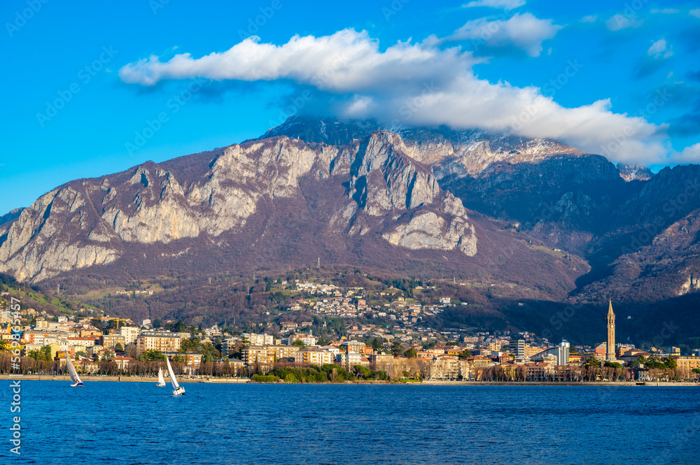 The city of Lecco, with its lakefront and its buildings, photographed in the evening.

