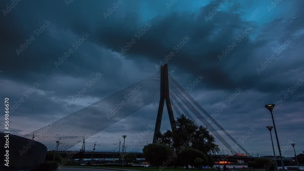 Silhouette of suspension bridge over Daugava river in Riga with storm clouds above