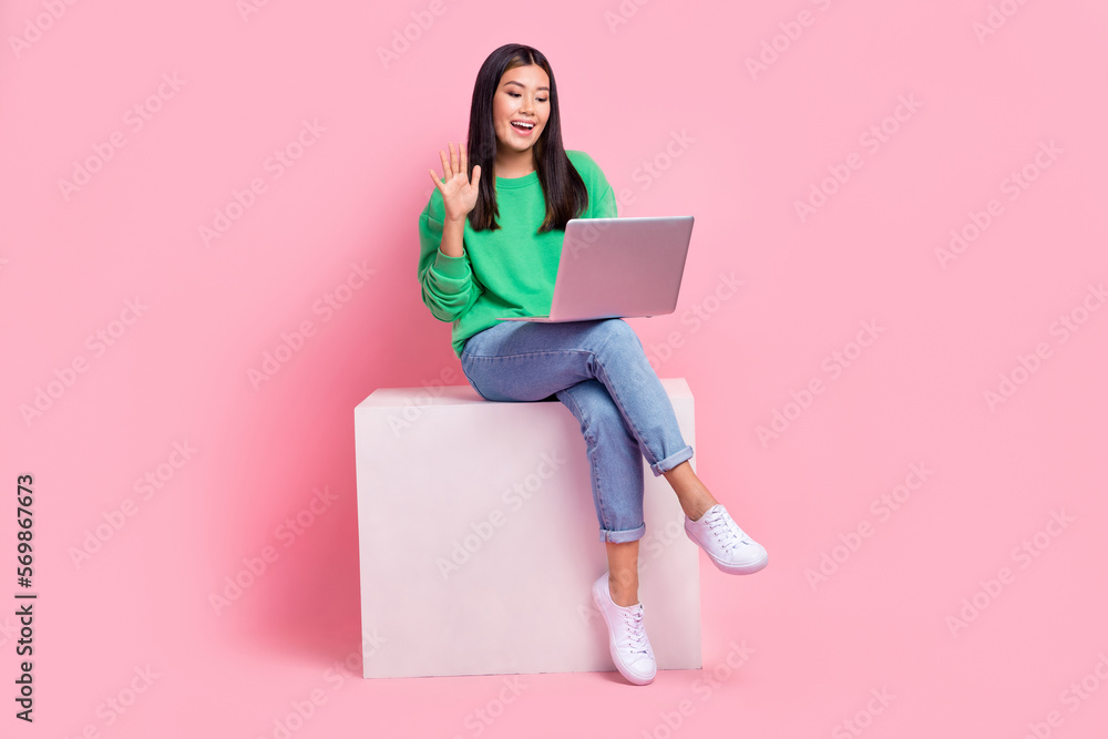 Full size portrait of nice cheerful girl sit podium arm waving communicate video call netbook isolated on pink color background Full size portrait of nice cheerful girl sit podium arm waving communicate video call netbook isolated on pink color background