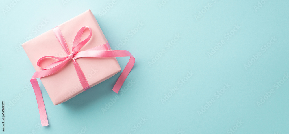 Saint Valentine's Day concept. Top view photo of pink giftbox with ribbon bow on isolated pastel blue background with copyspace