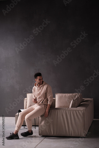 Happy stylish Afro American hipster guy portrait. Young Black man, student, self employed business owner with trendy haircut, glasses, toothy smile sitting on leather sofa at home. 