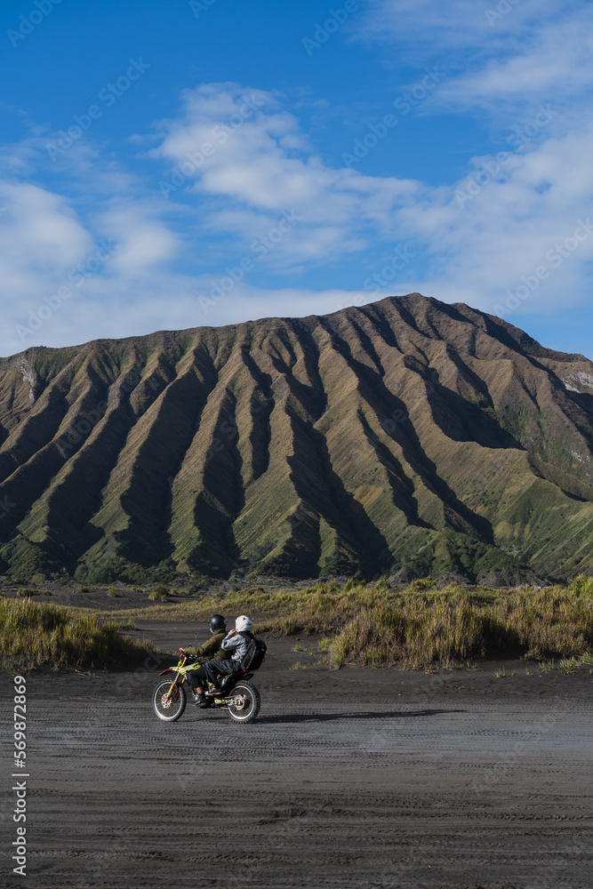 A motorbikewith two people driving in a amazing landscape with green hills as the background A motorbikewith two people driving in a amazing landscape with green hills as the background