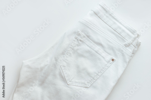 White denim pants on white background, jeans closeup, ripped denim