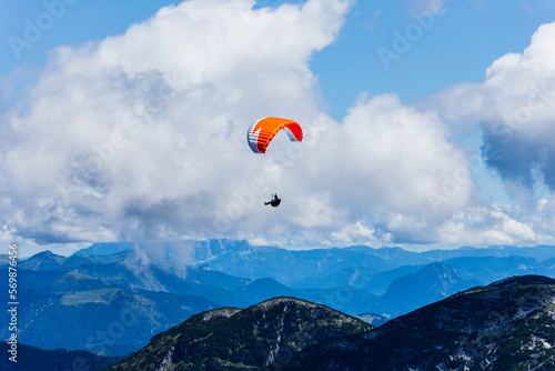 Paraglider flying over mountain peaks on a sunny day
