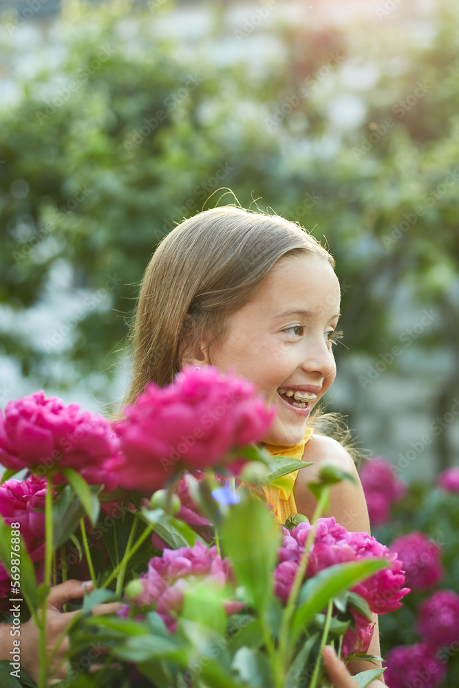 Happy little girl with braces in the garden in bushes of peonies Happy little girl with braces in the garden in bushes of peonies