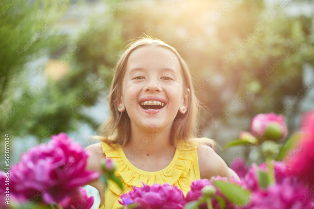 Happy little girl with braces in the garden in bushes of peonies Happy little girl with braces in the garden in bushes of peonies
