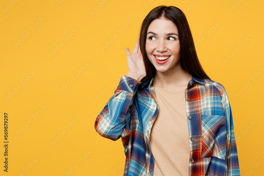 Fototapeta premium Young curious nosy smiling fun caucasian woman wear blue shirt beige t-shirt try to hear you overhear listening intently isolated on plain yellow background studio portrait. People lifestyle concept.