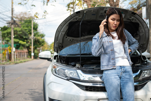 Angry Asian woman and using mobile phone calling for assistance after a car breakdown on street. Concept of vehicle engine problem or accident and emergency help from Professional mechanic © Prot